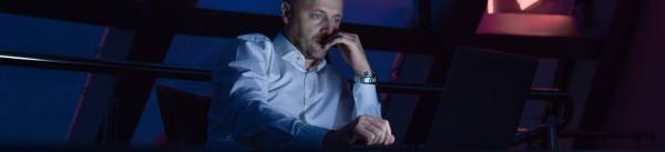 Businessman working on laptop in night office.